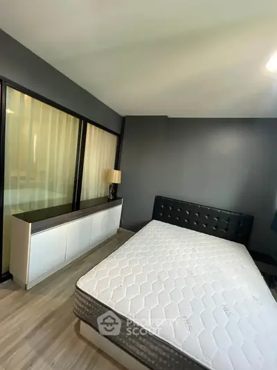 Modern bedroom with sleek design and large window, featuring a comfortable bed and stylish furniture.
