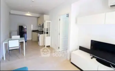 Modern open-plan living room with kitchen, featuring sleek furniture and appliances.