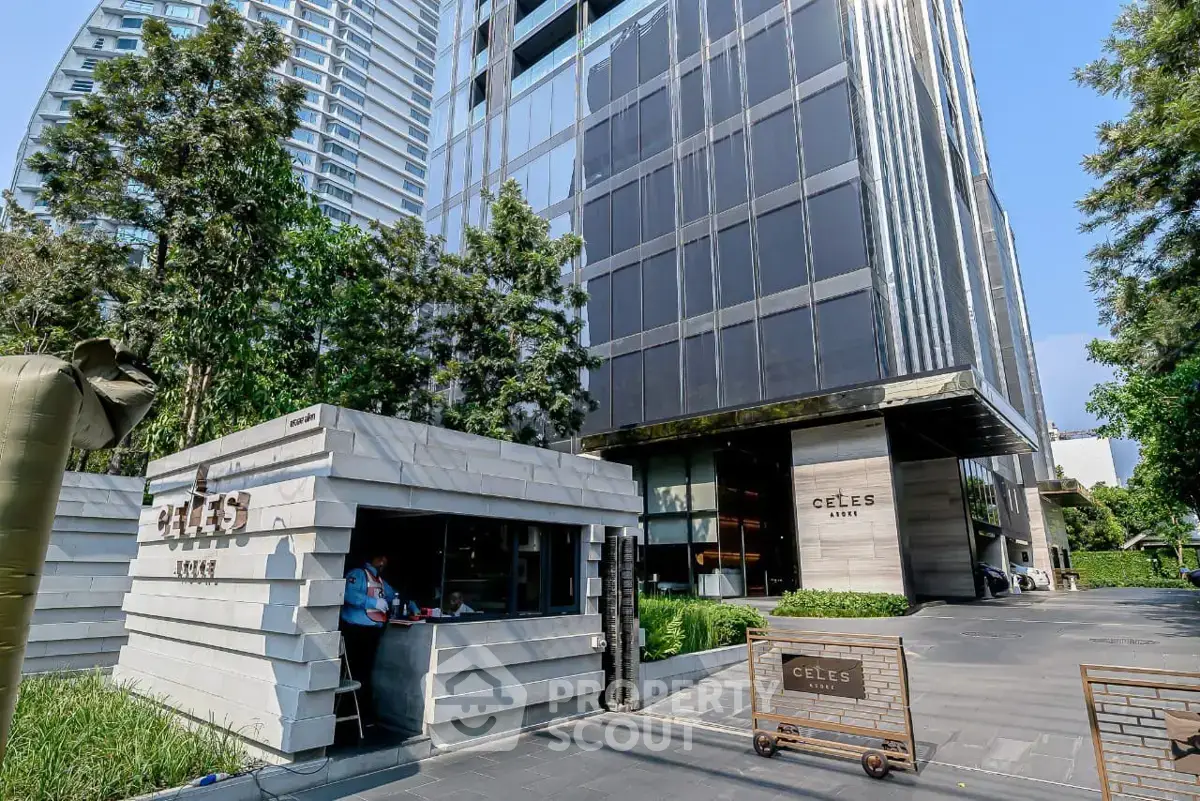 Modern high-rise building entrance with sleek design and lush greenery