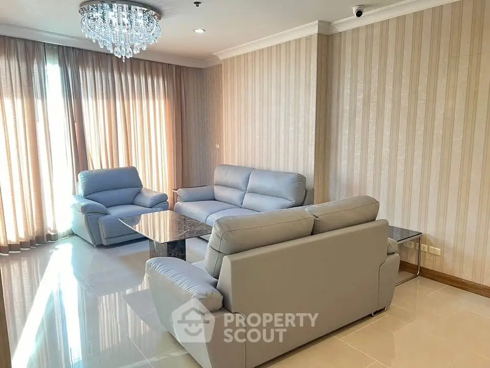Elegant living room with modern gray sofas and chandelier, featuring floor-to-ceiling curtains and glossy tiled flooring.