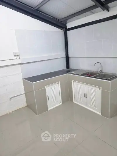 Modern minimalist kitchen with sleek countertops and dual sink in a compact layout.