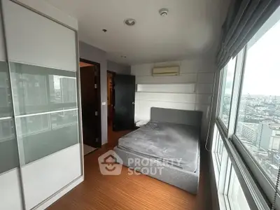Modern bedroom with city view, featuring sleek design and large windows for natural light.