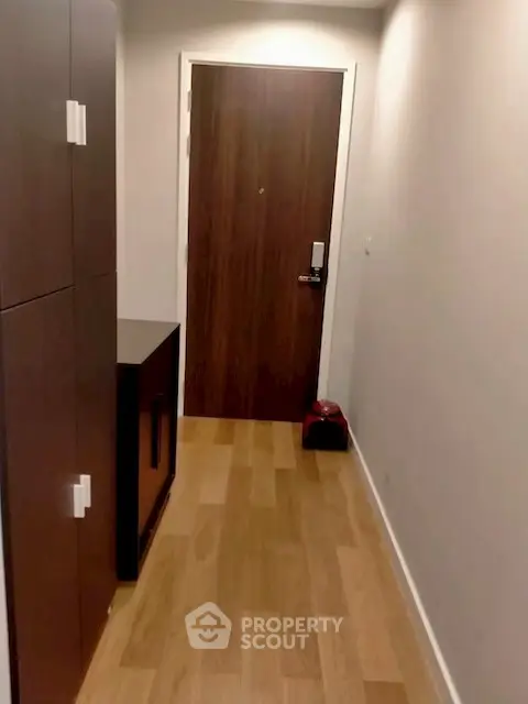 Modern apartment entrance with wooden flooring and sleek cabinetry