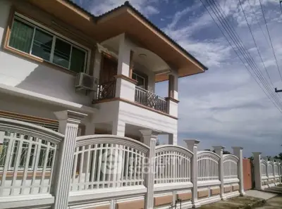 Elegant two-story house with balcony and decorative fence under a clear sky.