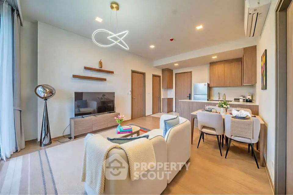 Modern open-plan living room with stylish decor and integrated kitchen area, featuring contemporary lighting and cozy seating.