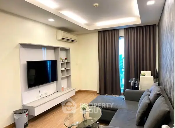 Modern living room with sleek furniture and large TV, featuring stylish lighting and a cozy ambiance.