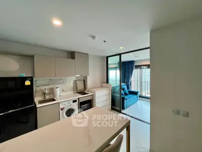 Modern kitchen with washing machine and open layout leading to a bright living area with balcony view.