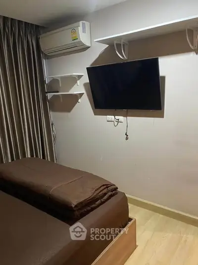 Cozy bedroom with wall-mounted TV and air conditioning, perfect for modern living.