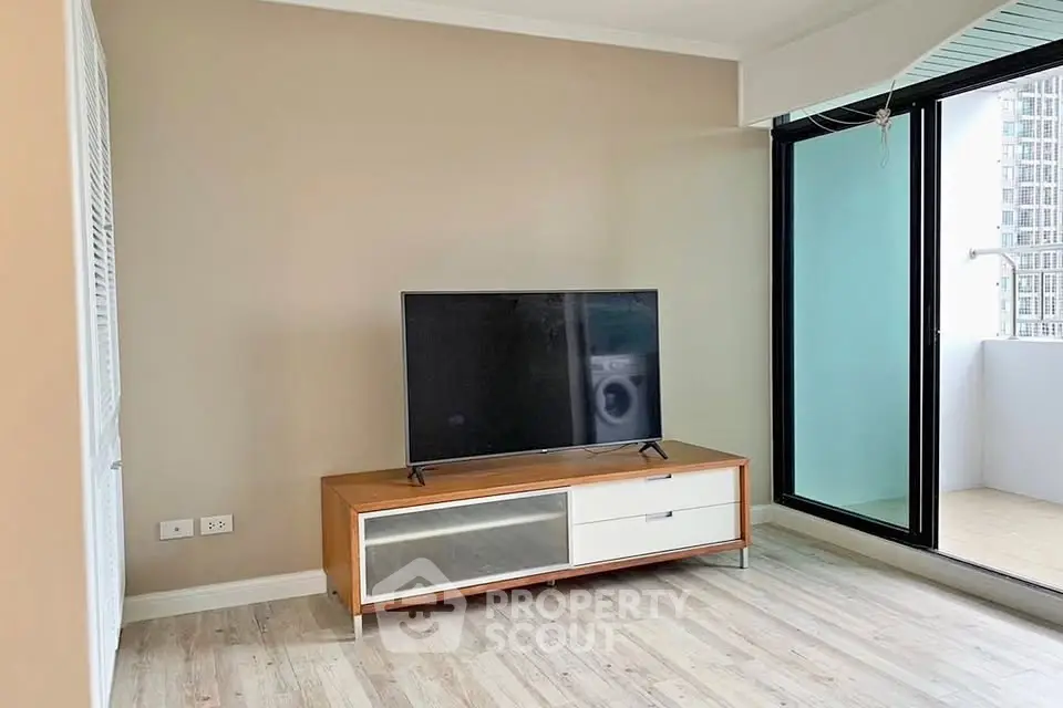 Modern living room with sleek TV stand and access to balcony, featuring stylish flooring and neutral walls.