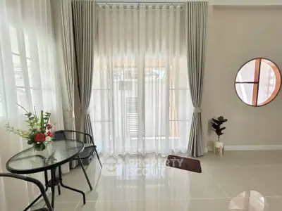 Elegant living room with sheer curtains and modern decor, featuring a cozy seating area and stylish round mirror.