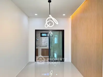 Modern minimalist interior with sleek lighting and sliding glass doors leading to a stylish kitchen.