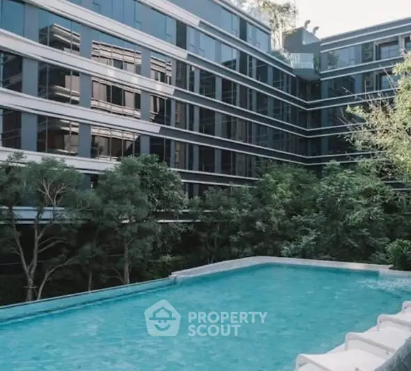 Luxurious modern building with a serene pool and lush greenery