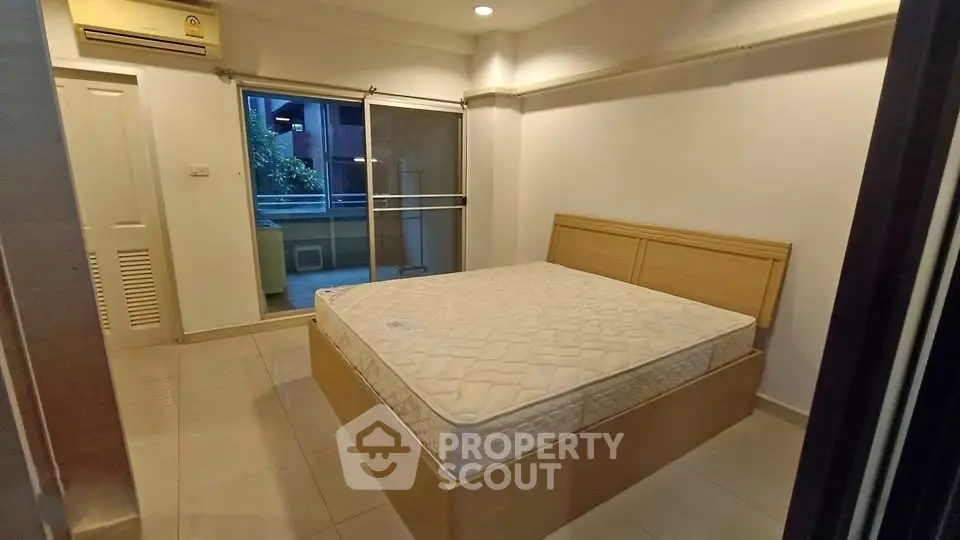 Spacious bedroom with large window and balcony access in modern apartment.