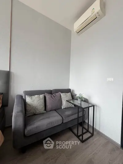 Modern living room with sleek gray sofa and air conditioning unit, perfect for cozy relaxation.
