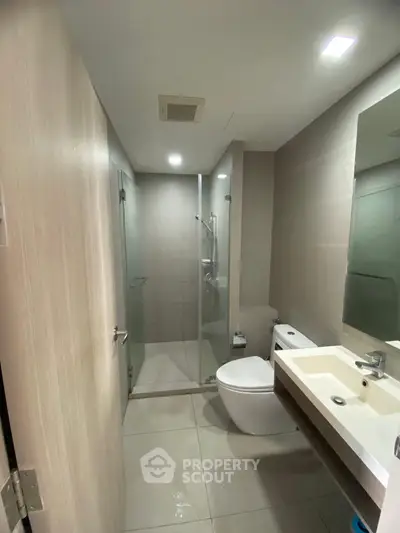 Modern bathroom with glass shower and sleek fixtures in contemporary apartment.