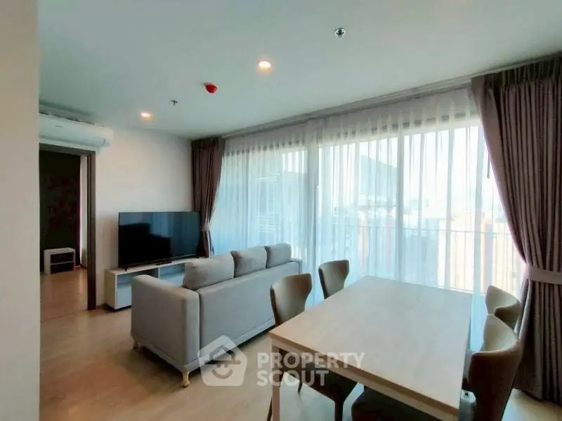 Spacious living room with large windows and modern furniture in a bright apartment.