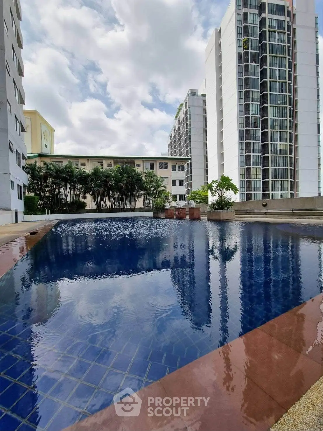 Luxurious residential pool with modern high-rise buildings and lush greenery.