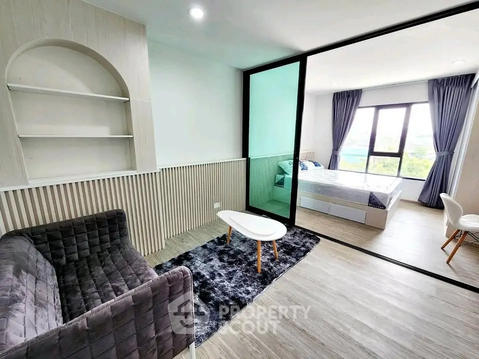 Modern apartment interior with stylish living room and cozy bedroom separated by glass partition.