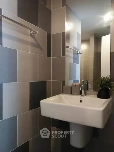 Modern bathroom with sleek sink and stylish tiled walls in neutral tones.