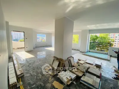 Spacious open-plan living area with large windows and balcony access, ideal for modern living.