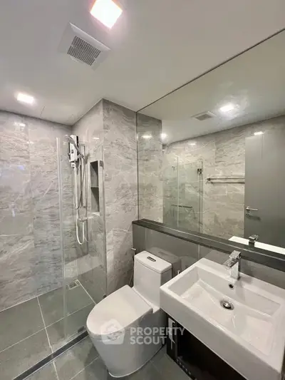 Modern bathroom with sleek design, featuring a glass shower enclosure and elegant fixtures.