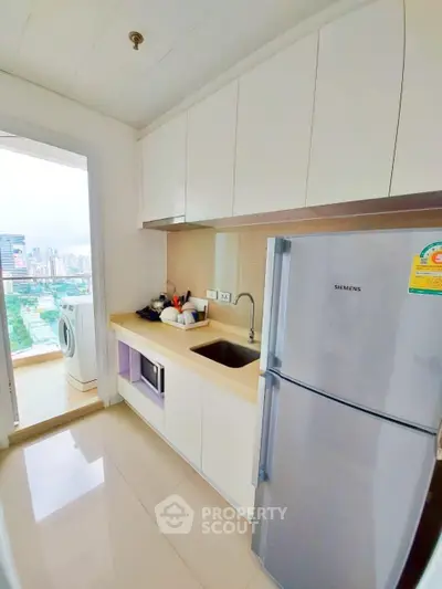 Modern kitchen with sleek cabinets and appliances, featuring a city view from the balcony.