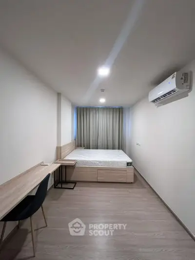 Modern minimalist bedroom with sleek furniture and air conditioning, perfect for comfortable living.