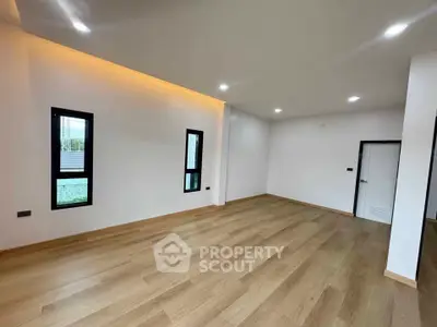 Spacious empty room with wooden flooring and modern lighting, ideal for customization.