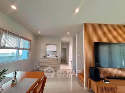 Modern living room with sleek design and large TV, featuring wooden accents and ample natural light.