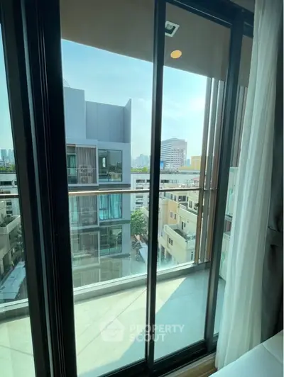 Modern apartment balcony with city view and glass sliding doors.