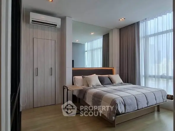 Modern bedroom with stylish decor and large windows offering city views.