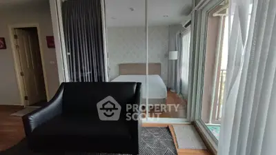 Modern bedroom with glass partition and stylish black sofa, featuring elegant decor and natural light.