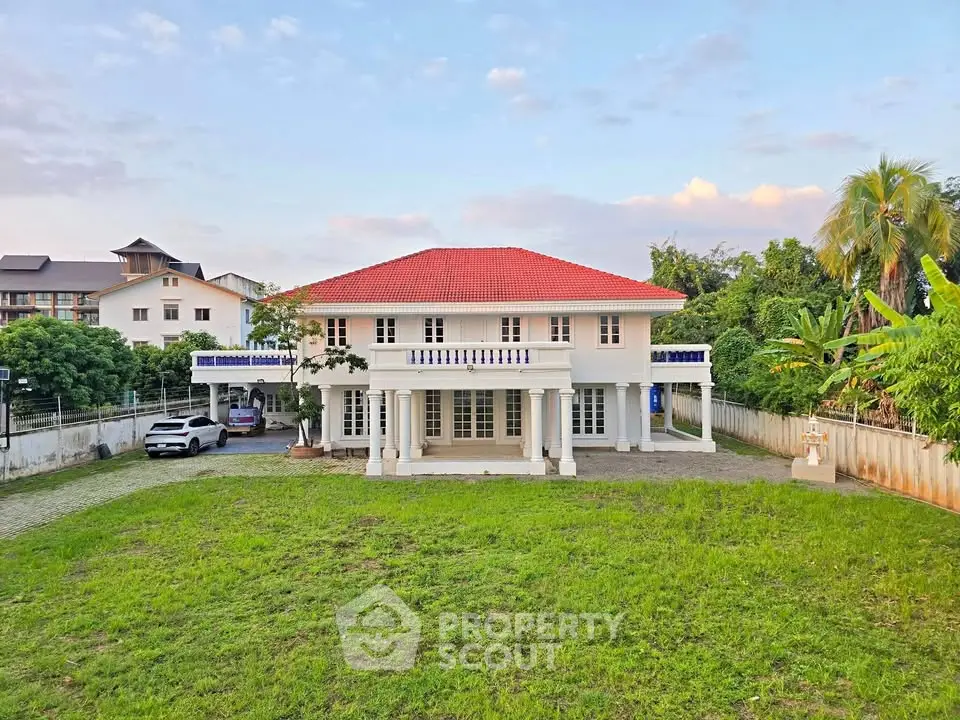 Stunning two-story house with red roof and spacious green lawn, perfect for family living.