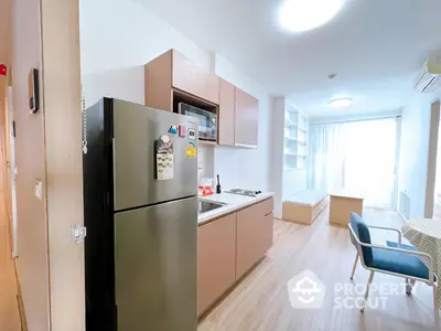 Modern kitchen with stainless steel appliances and ample cabinetry, seamlessly opening to a cozy living area with natural light.