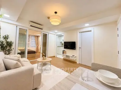Modern living room with cozy sofa and TV, open to bedroom view