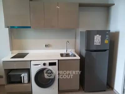Modern kitchen with integrated appliances including washing machine and fridge, sleek cabinetry design.