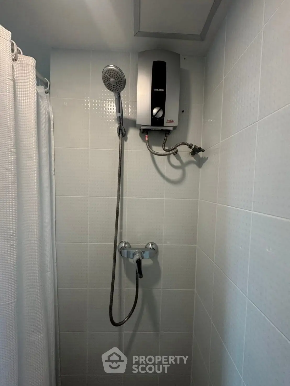 Compact bathroom shower area with water heater and tiled walls