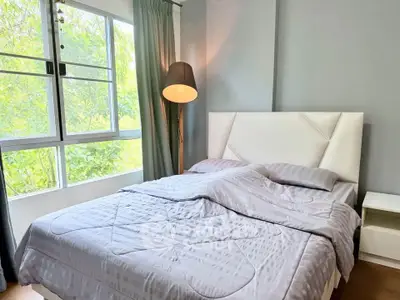 Cozy bedroom with large window and stylish decor, perfect for relaxation and comfort.