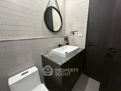 Modern bathroom with sleek design featuring a round mirror and stylish fixtures.