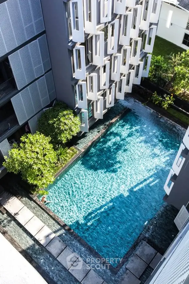 Modern apartment building with a stunning pool and unique architectural design.