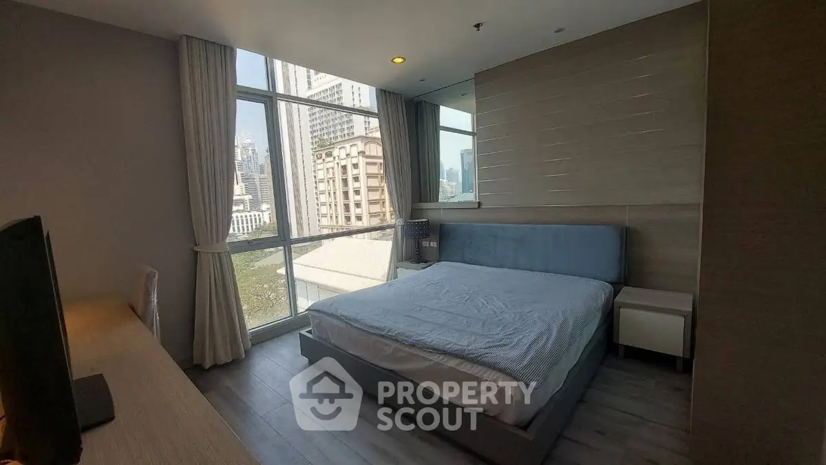 Modern bedroom with large window and city view in high-rise apartment