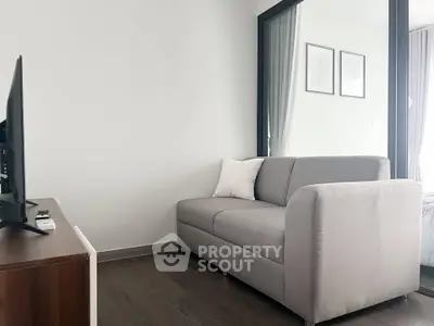Modern living room with sleek gray sofa and wall-mounted TV, perfect for cozy relaxation.