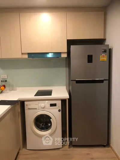Modern kitchen with sleek appliances including washing machine and fridge, featuring a minimalist design.