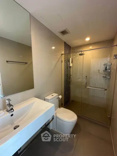 Modern bathroom with glass shower and sleek fixtures in a contemporary apartment.