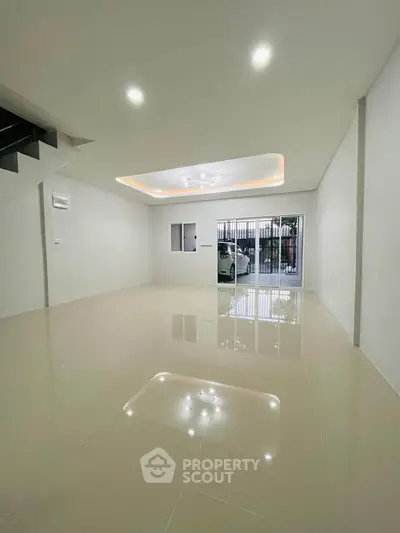 Spacious modern living room with glossy tiled floors and recessed lighting, featuring a large window for natural light.