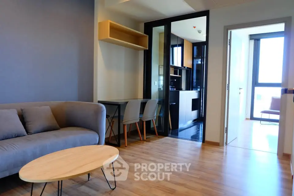 Modern living room with sleek furniture and open kitchen layout in a stylish apartment.