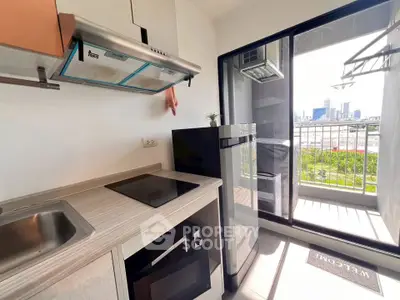 Modern kitchen with sleek appliances and balcony view of city skyline.