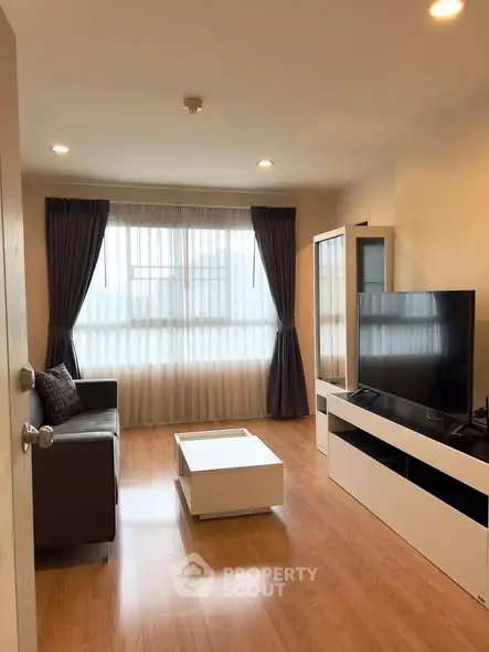 Modern living room with large window, sleek furniture, and wooden flooring.