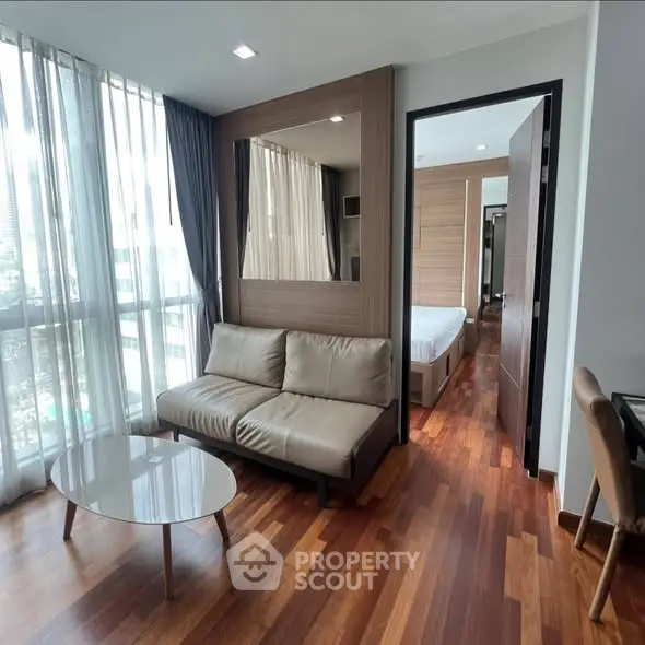 Modern living room with wooden flooring and city view, featuring a cozy sofa and stylish decor.