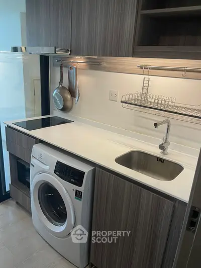 Modern kitchen with sleek cabinetry, washing machine, and induction cooktop in a compact layout.